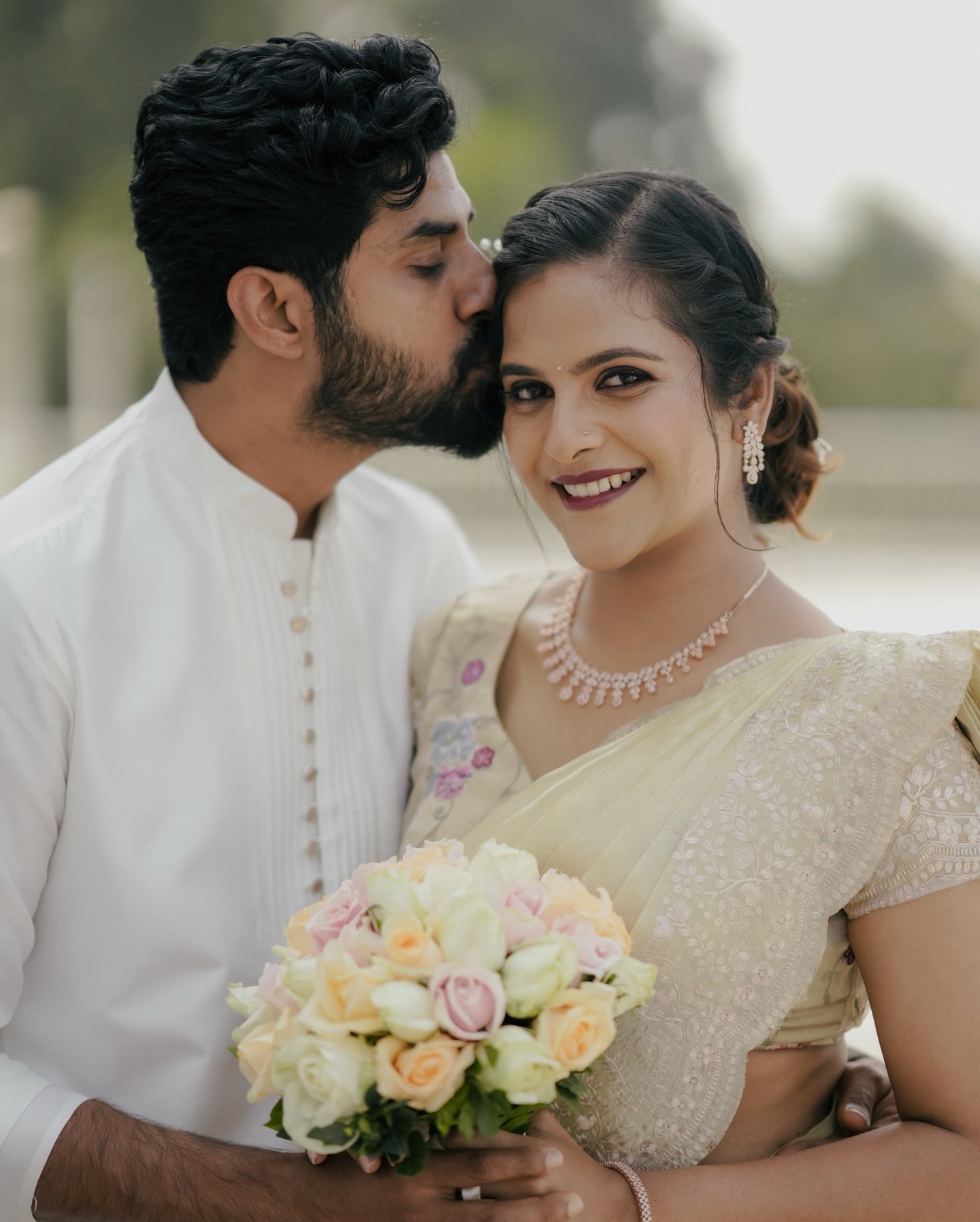 A groom kissing his smiling bride on the forehead